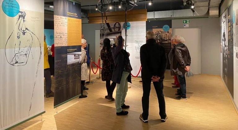 Menschen stehen in der Ausstellung im Schwebodrom und unterhalten sich. 