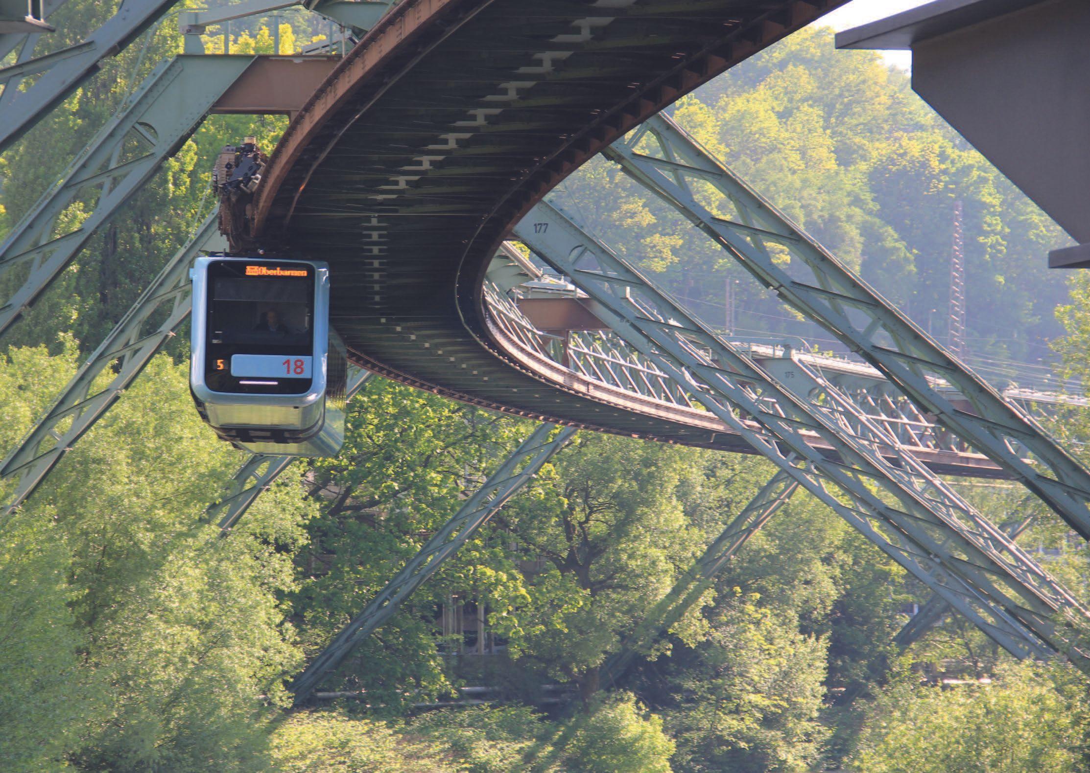Die Schwebebahn fährt durch einen grünen Abschnitt der Strecke. 