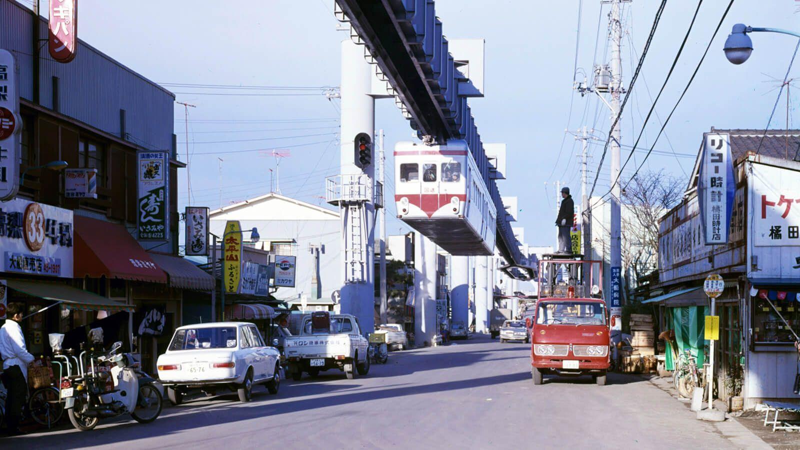 Erste Bilder des Shonan Railway über einer kleinen, fast dörflichen Straße. 